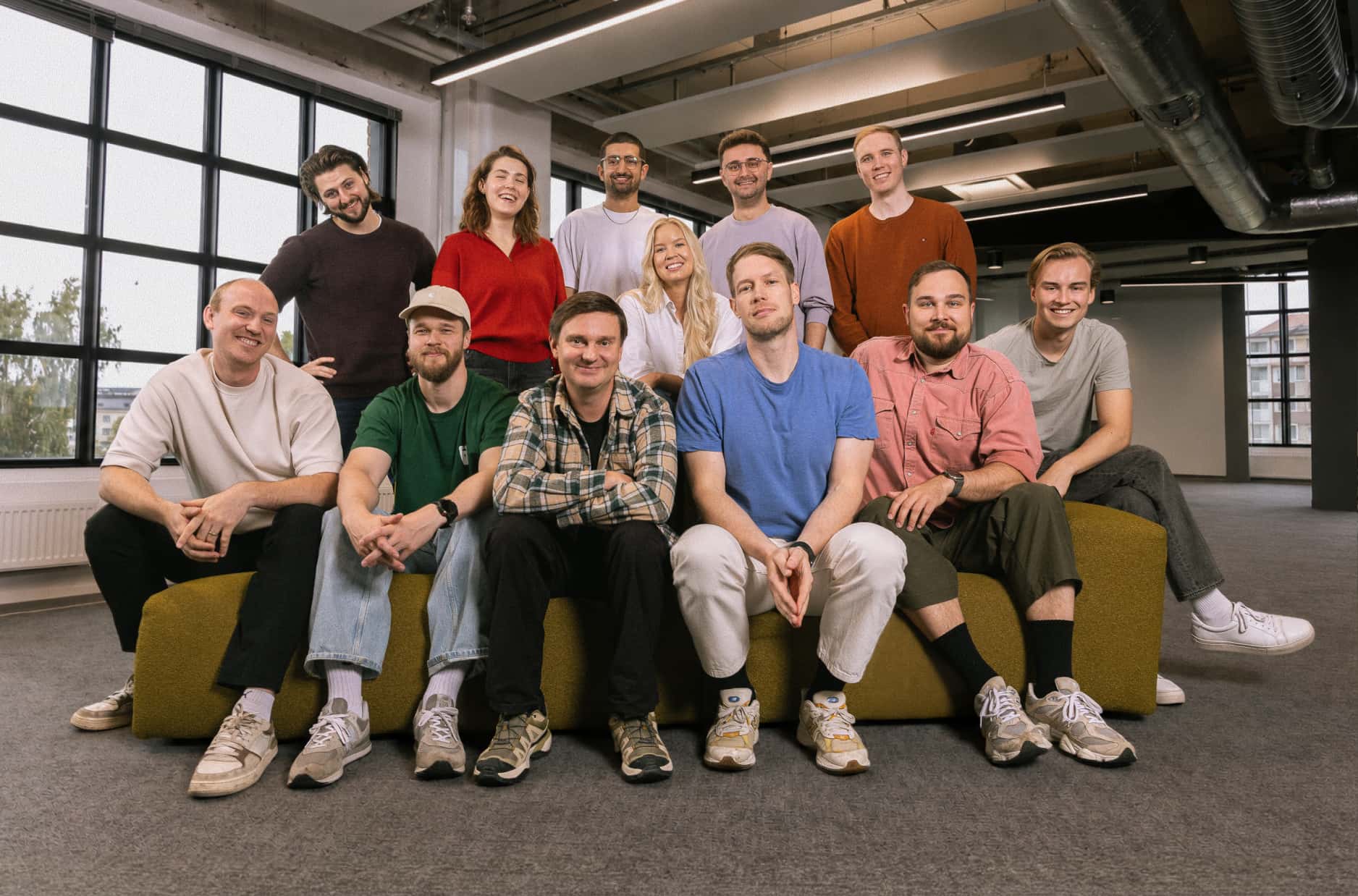 The Zero team sitting together on a yellow sofa in the Helsinki office